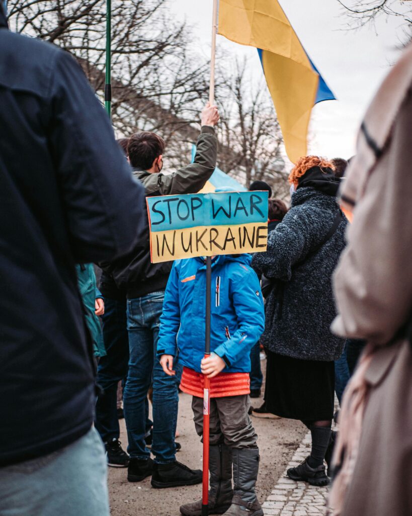 A child holds a 'Stop War in Ukraine' sign during a peaceful protest outdoors in Berlin, Germany.